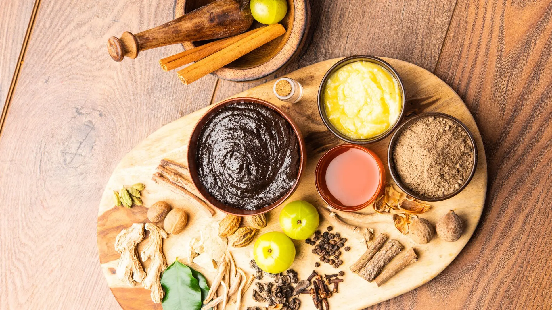Ayurvedic herbs, powders, ghee, and herbal paste on a wooden board, representing Bhaishajya Kalpana and traditional Ayurvedic medicine preparation
