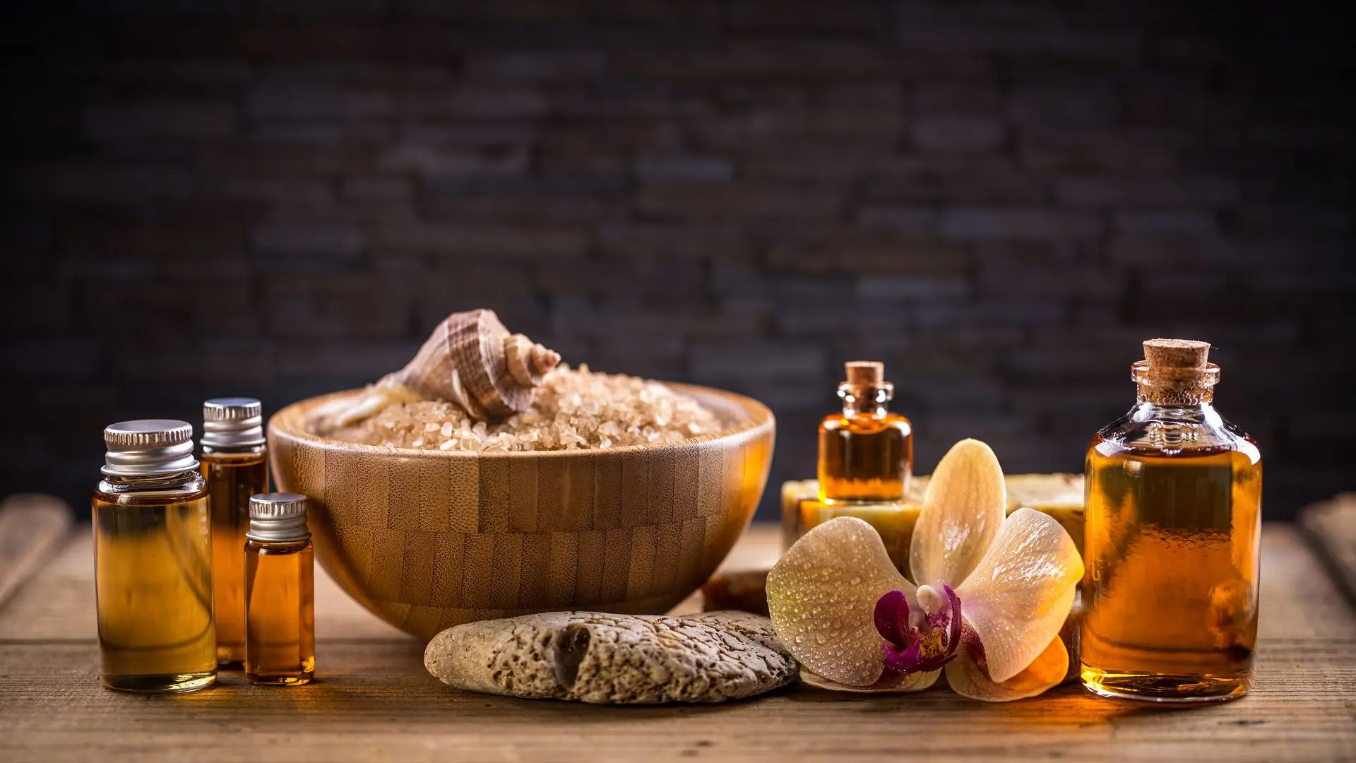 Ayurvedic medicated oils in glass bottles with herbs, sea salt, and flowers on a wooden surface, representing natural healing and traditional wellness remedies